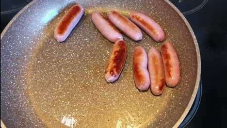 Overhead-shot-of-flipping-cooking-sausage-on-frying-pan