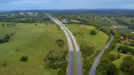 Cars-Driving-And-Travelling-At-Pacific-Motorway-Carriageway-By-Green-Hills-And-Fields-In-Byron-Bay,-Australia