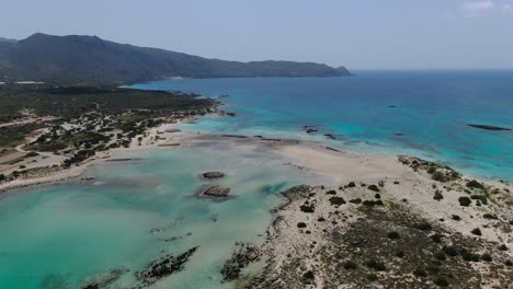 Lagoon-at-Elafonissi-Beach-in-Crete-Greece-with-rocky-shoreline,-Aerial-dolly-out-shot