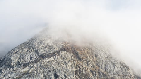 Sonnenlicht-Scheint-Auf-Die-Steile-Felswand-Des-Berges-In-Grönland,-Bevor-Wolken-Und-Nebel-Den-Gipfel-Verbergen,-Während-Schlechtes-Wetter-über-Die-Landschaft-Zieht