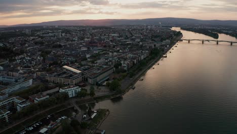 Approaching-the-Dom-church-of-Mainz-with-the-Rhine-river-with-and-reflections-on-the-water-and-bridge-in-the-background-on-a-sunny-summer-night-by-a-drone