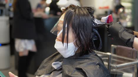 Asin-Frau,-Die-Eine-Weiße-Virusschutzmaske-Trägt,-Während-Sie-Während-Der-Covid-19-pandemie-Eine-Haarmaskenbehandlung-Im-Beauty-Spa-Salon-In-Südkorea-Anwendet