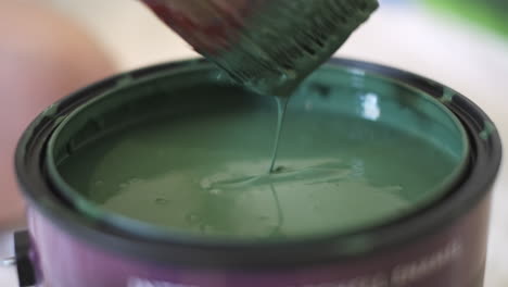 close-up-of-paint-brush-dipping-into-green-paint-in-can---isolated