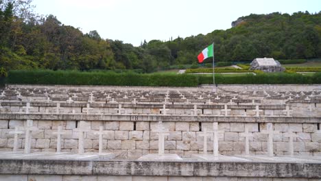 View-of-single-red,-white-and-green-Italian-flag-above-rows-of-white-stone-cross-above-several-tombs-at-Polish-cemetery,-Monte-Cassino,-Italy,-static
