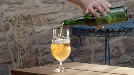 Male-arm-carelessly-pours-and-spills-beer-from-bottle-to-glass
