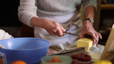 old-lady-slicing-butter-as-she-bakes-in-a-home-kitchen