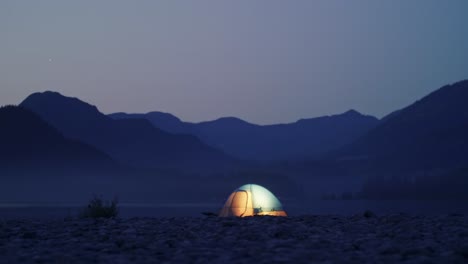 Light-in-illuminated-tent-with-mountain-background-glows-then-goes-out