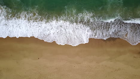 Top-down-aerial-view-of-waves-breaking-on-the-coast,-calming-perspective,-drone