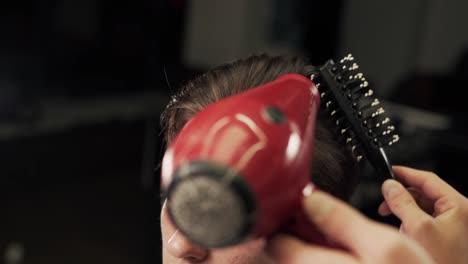 Male-hands-of-the-master-of-a-haircut-put-long-hair-by-the-hair-dryer