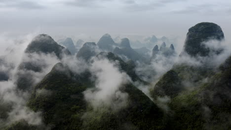 Karst-mountains-covered-in-clouds,-aerial-view