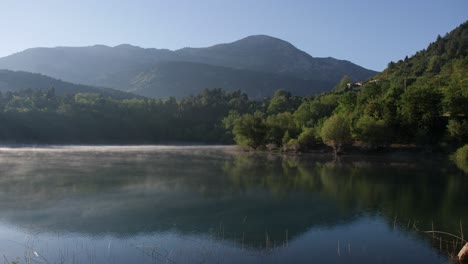 Hermosa-Vista-Panorámica-Del-Lago-Rural-De-Niebla-Baja,-Bosque-Verde-Y-Montaña-En-El-Fondo,-Estática