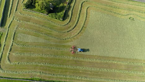 Drone-Ascends-Overhead-in-Birdseye-Revealing-Epic-Fields-that-Farmer-is-working-in-his-Blue-Tractor,-Aerial