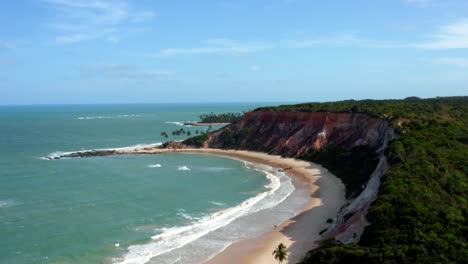 Amazingly-gorgeous-aerial-drone-left-trucking-shot-of-the-tropical-beach-of-Tabatinga-with-large-colorful-cliffs,-green-water,-and-beautiful-sand-near-Joao-Pessoa,-Brazil-on-a-warm-sunny-summer-day