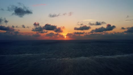 Beautiful-aerial-drone-shot-of-a-serene-ocean-sunrise-at-Well-Beach-near-Joao-Pessoa-on-a-warm-summer-morning-with-the-water-below-and-golden-clouds-on-the-skyline