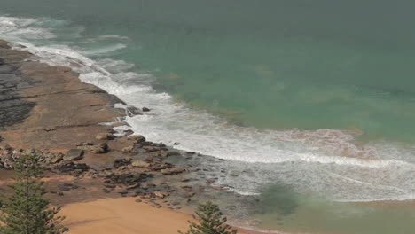 Waves-crashing-on-rocky-beach,-static-side-angle,Whale-beach