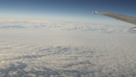 Vista-Aérea-De-Las-Nubes-Por-La-Ventana-Del-Avión-Con-Tiro-De-Ala-En-4k-De-Alta-Resolución