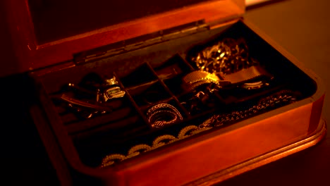 Opening-a-box-of-gold-jewelry-in-an-atmospheric-shot,-elegant-and-classy
