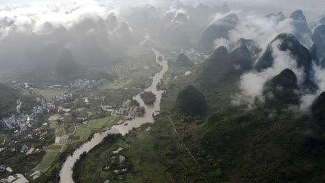 Chinese-countryside-town-in-Yulong-river-mountain-valley,-high-aerial-view