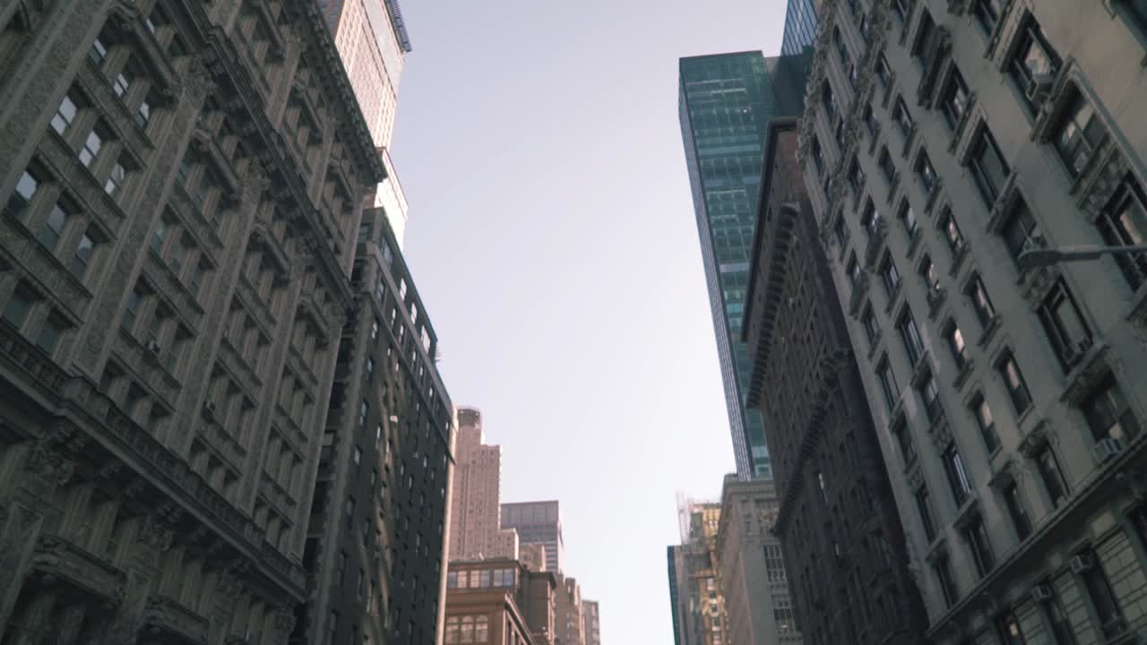 interesting perspective looking up at a mix of old and modern buildings  lining a street in new york city, usa