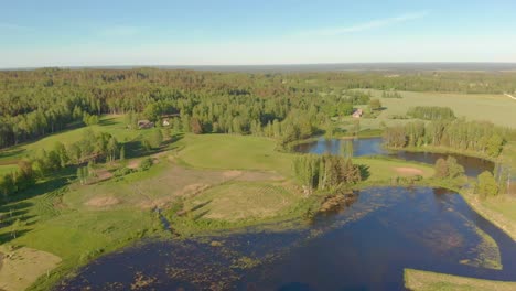 Slow-flying-drone-aerial-over-lakes-at-the-edge-of-a-forest-in-Latvia's-Kurzeme
