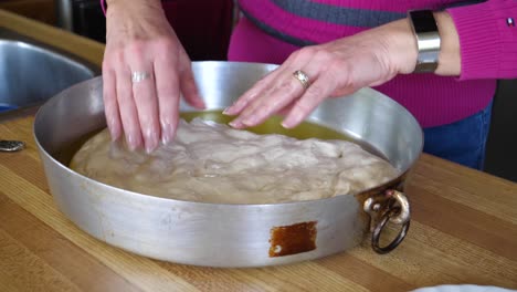 Hands-Spreading-Focaccia-Dough-Into-Metal-Pan---Homemade-Baking-60fps