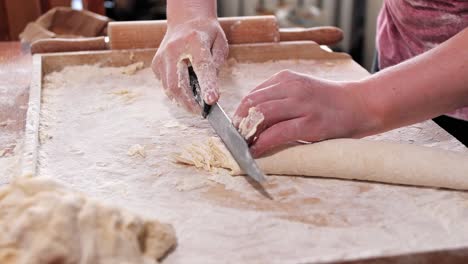Woman,-housewife,-cuts-the-roll-of-dough-into-thin-strips-with-a-knife