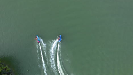 Two-jetsurf-riders-enjoying-extreme-racing-and-chasing-each-other,-aerial-god-view