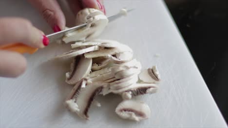 Slicing-mushrooms-on-a-chopping-board-close-up