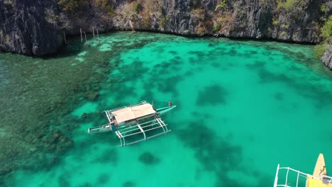 Male-Standing-on-Boast-in-Ecotic-Tropical-Lagoon-of-Coron-Island,-Philippines,-Static-Aerial-View