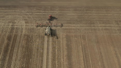 Saattraktor,-Der-An-Einem-Sonnigen-Morgen-Auf-Dem-Riesigen-Ackerland-In-Saskatchewan,-Kanada,-Arbeitet---Statischer-Drohnenschuss