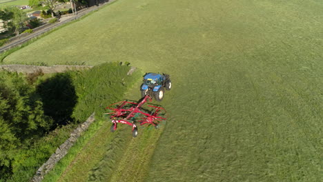 Drone-Tracks-a-Farmer-working-his-land-in-a-Blue-tractor-in-a-Beautiful-Green-West-Yorkshire-Farm-during-the-day,-Aerial