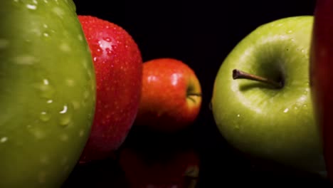 forwards-fast-moving-macro-view-past-apples-with-black-isolated-background,-stunning-footage-of-heatly-fruit