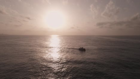 Luftaufnahme-Silhouettiertes-Boot,-Das-über-Einen-Dramatisch-Schimmernden-Sonnenuntergang-Fährt