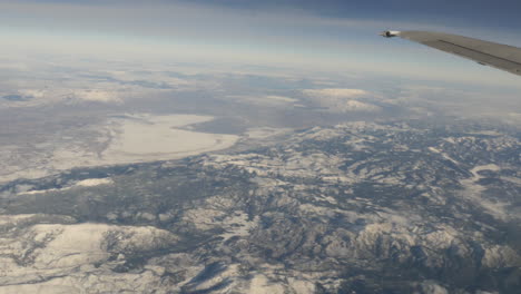 Vista-Aérea-De-Montañas-Cubiertas-De-Nieve-Desde-La-Ventana-De-Un-Avión-Volador-Filmada-En-Alta-Resolución-De-4k
