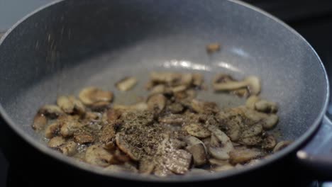 Adding-spices-on-a-frying-mushrooms-in-a-pan