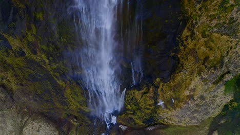 Inclinando-Una-Enorme-Cascada-En-Islandia-Para-Revelar-La-Cima-Del-Acantilado-Donde-El-Agua-Glacial-Se-Vierte-Sobre-El-Borde-De-La-Montaña