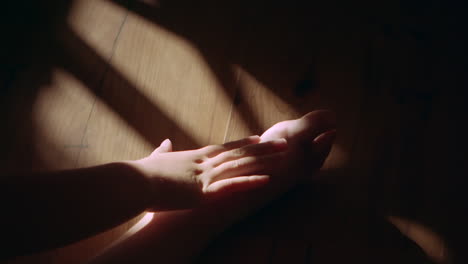 Caring-for-injured-ankle-in-dark-dramatic-indoor-light,-slow-motion