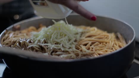 Mincing-Parmesan-cheese-on-spaghetti-in-a-frying-pan