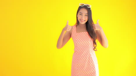 Portrait-of-Attractive-Asian-Female-Isolated-on-Yellow-Background-Showing-Thumbs-Up,-Static-Shot