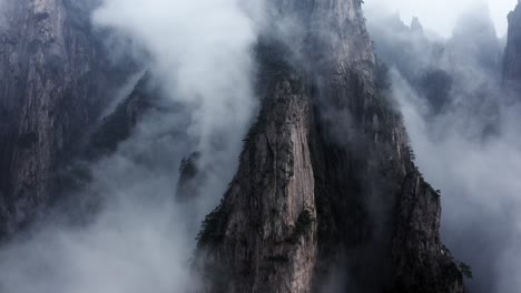 Huangshan-mountain-peaks-rising-up-above-clouds,-Anhui-China,-aerial