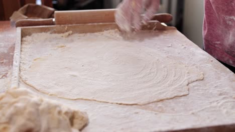 Woman,-housewife,-sprinkles-flour-on-the-rolled-dough