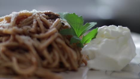 Adding-A-Leaf-Of-Italian-Parsley-To-A-Plate-Of-Delicious-Spaghetti-With-Mozzarella-On-The-Side---close-up