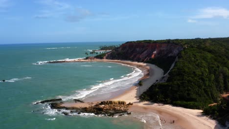 Amazingly-gorgeous-aerial-drone-lowering-shot-of-the-tropical-beach-of-Tabatinga-with-large-colorful-cliffs,-green-water,-and-beautiful-sand-near-Joao-Pessoa,-Brazil-on-a-warm-sunny-summer-day