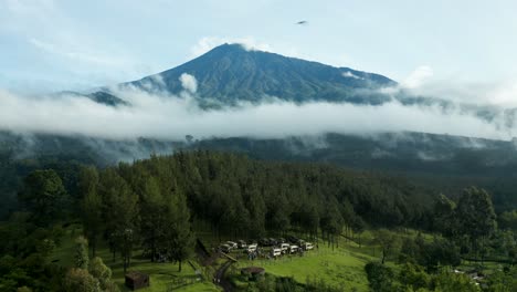 Drone-Pan-Aéreo-Disparado-Por-Encima-De-Los-árboles-Que-Revelan-El-Bosque-Y-El-Horizonte-De-La-Montaña-Mirando-Un-Volcán-Y-Nubes-Hermosa-Naturaleza-Selva-De-Tanzania-4k