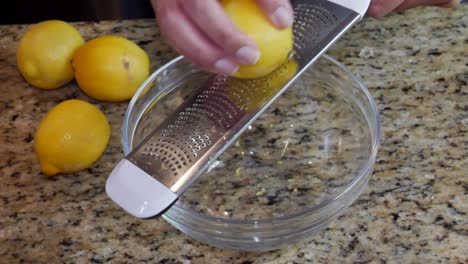 Frau,-Die-Zitrone-Mit-Einer-Metallreibe-In-Eine-Klare-Glasschüssel-Reibt