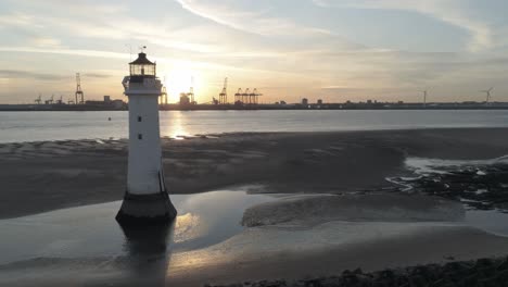 Aerial-static-view-across-British-Lighthouse-and-coastal-shipyard-cranes-sunrise-skyline
