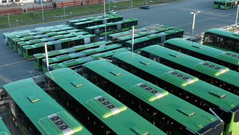 Autobuses-Eléctricos-Verdes-Alineados-En-El-Parque-De-Autobuses,-Vista-Aérea-De-Drones