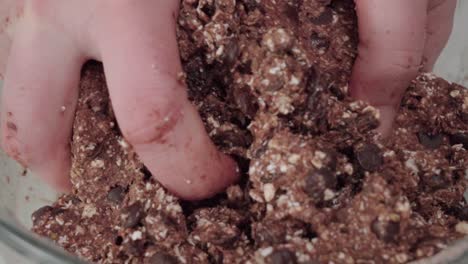 Mixing-chocolate-oatmeal-cookie-dough-with-hands,-Extreme-Closeup