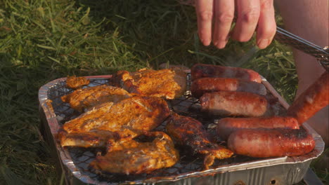 Person-flips-over-meats-on-bbq-grill-at-golden-hour,-close-up