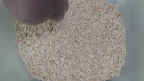 Pouring-Half-Cup-of-Quick-Oats-into-Bowl,-Overhead-Closeup